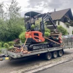 Minibagger Eurocomach 18ZT mit Dumper verladen auf Anhänger vor Wohnhaus – Tritten Baggervermietung liefert Maschinen direkt im Zürcher Oberland