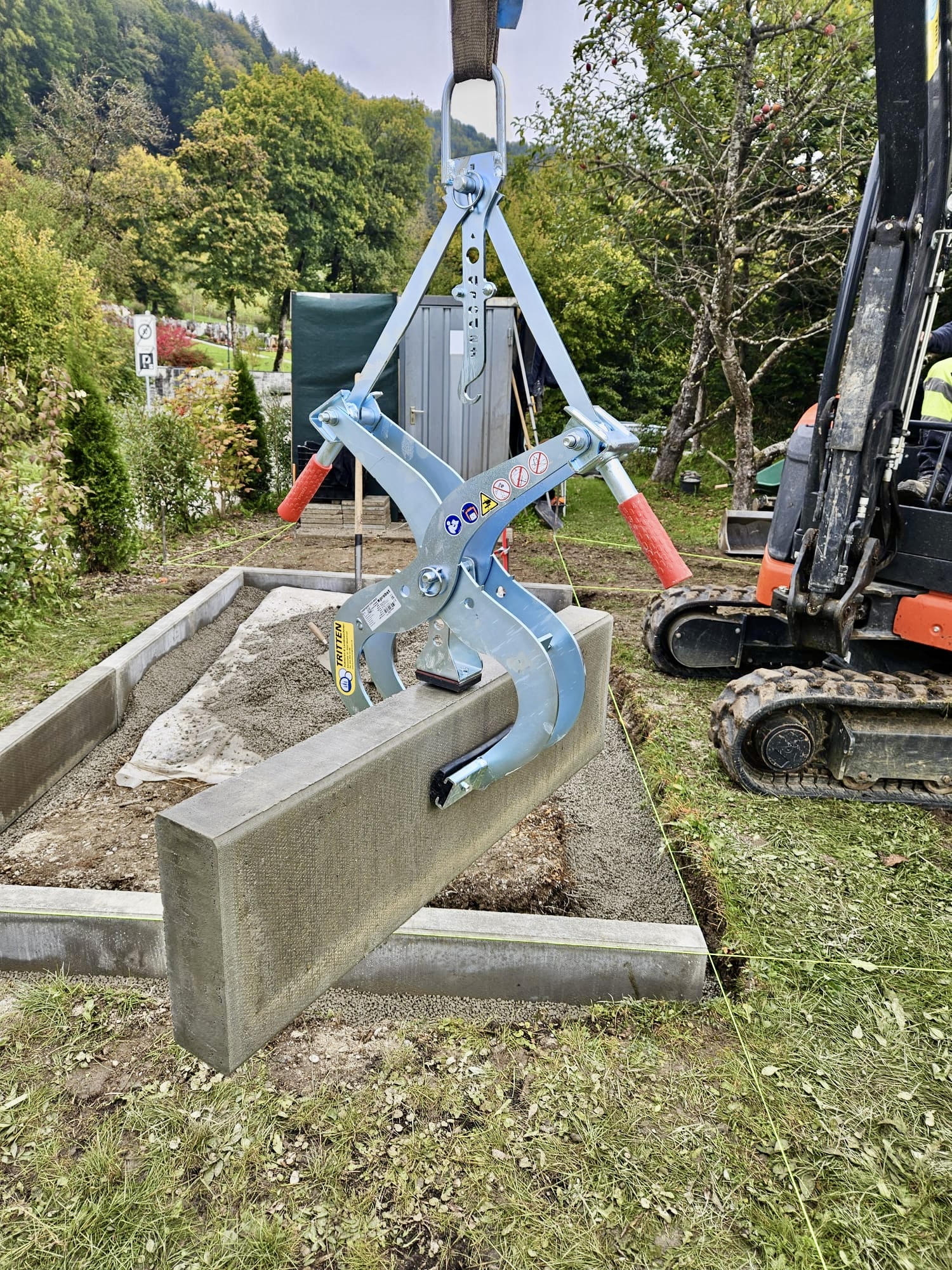 Steinzange beim präzisen Setzen eines Randsteins mit Bagger auf Baustelle – Mietgerät von Tritten Baggervermietung Schweiz