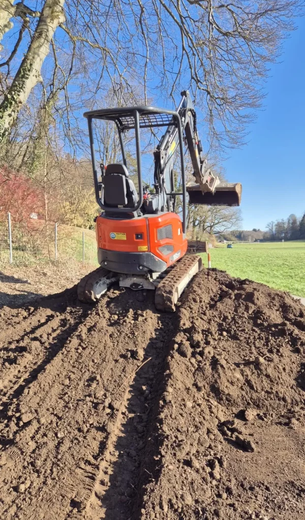 Oranger 1.8t Minibagger von Tritten Baggervermietung bei Aushubarbeiten auf einer Baustelle im Zürcher Oberland